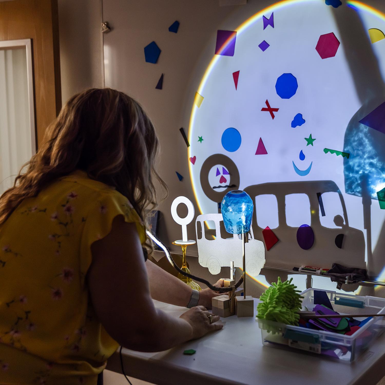An educator observes the shadows made by a directed light as part of an interactive STEAM exhibit.